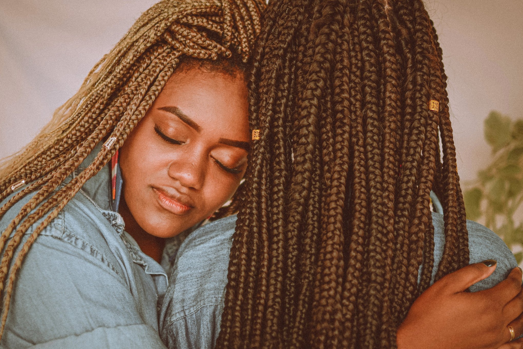 Two afro women with braids hugging each other